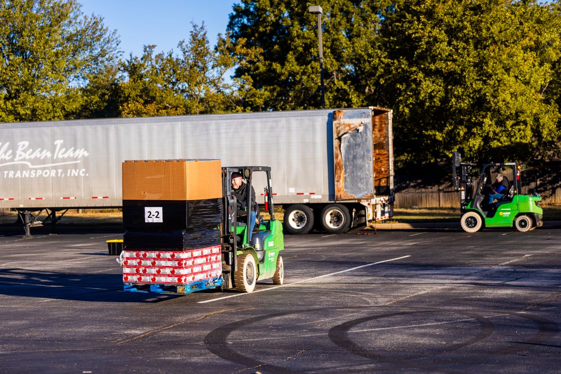 Reference photograph of forklift operators loading pallets beside a truck